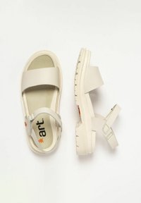 Sandalias beige con una suela texturizada, que cuentan con dos correas anchas y una correa ajustable en el tobillo. Logo impreso en la planta.