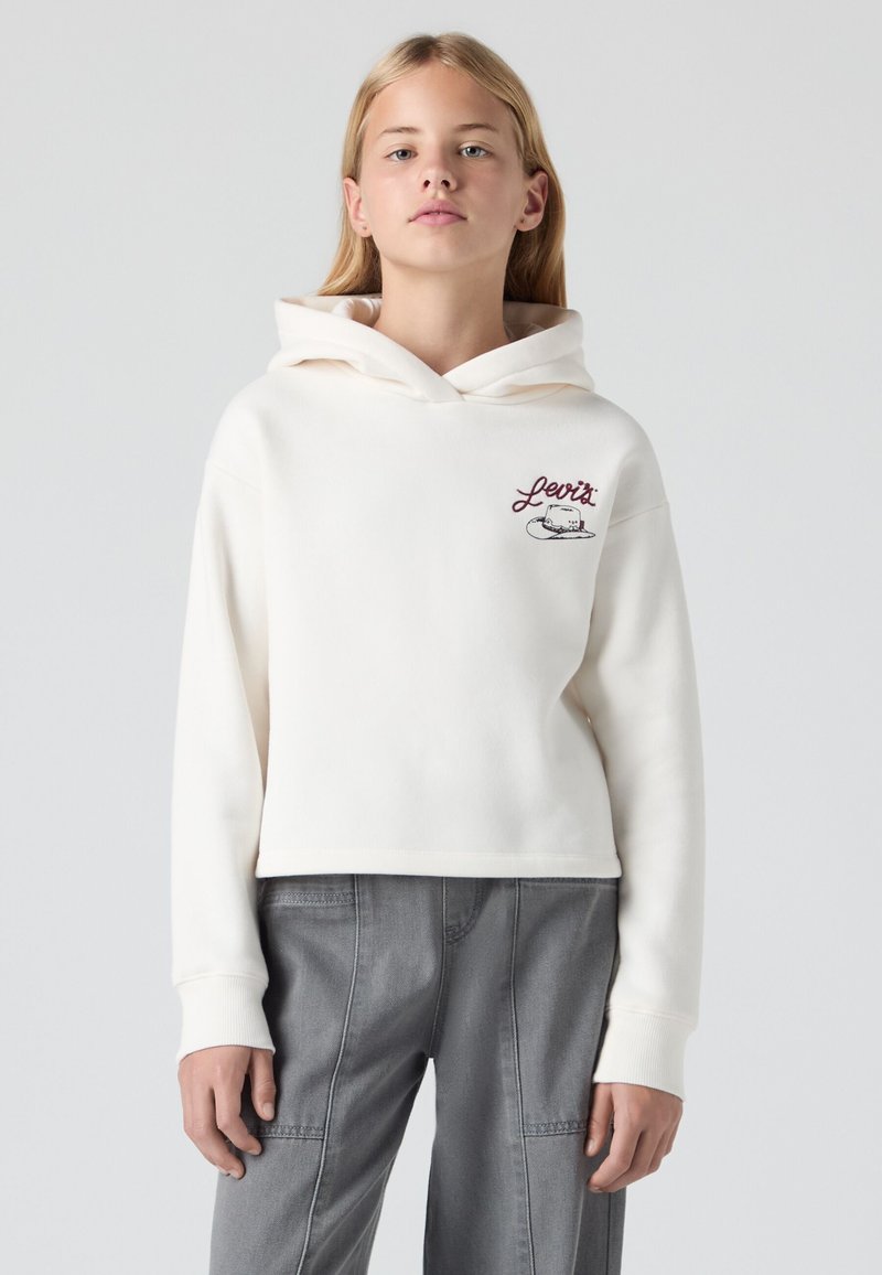 Manta-pear cropped hoodie creme com um bolso frontal e logotipo bordado. Material de algodão suave, mangas longas e capuz com cordão.