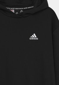 Schwarzer Hoodie aus glattem Stoff mit einem weißen Adidas-Logo auf der linken Brust und einer gefütterten Kapuze mit wiederholtem Branding innen.