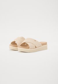 Beige vävda slidesandaler med tvärsregistrering, plattformssula och en strukturerad ovandel. Har en lätt vadderad innersula för komfort.