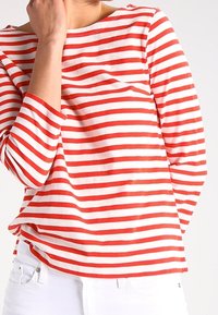 Rot-weiß gestreiftes Langarmshirt aus Baumwolle mit einem Bootsausschnitt, das einen lockeren Schnitt und eine weiche Textur bietet.