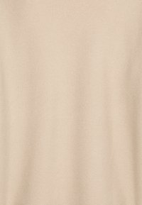 Beige Strickstoff mit strukturierter Oberfläche; gleichmäßige Farbdurchmischung mit einem glatten, leicht gerippten Erscheinungsbild.