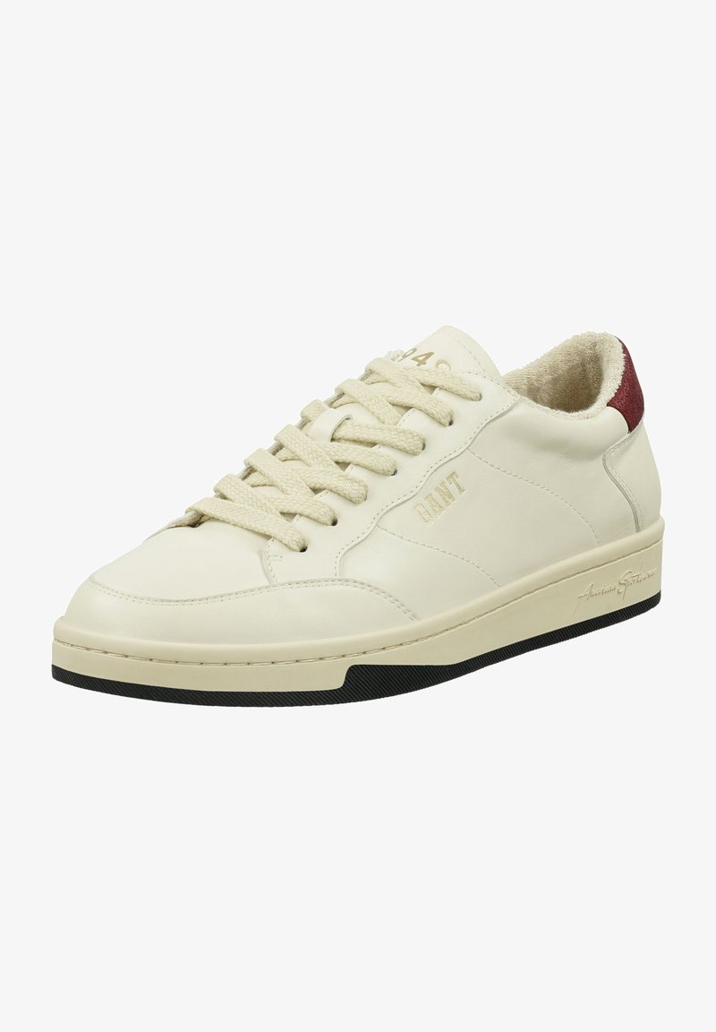 Baskets en cuir blanc avec des accents beiges, présentant un bout rond, des lacets texturés, une doublure douce et une semelle extérieure en caoutchouc noir. Détail logo doré.