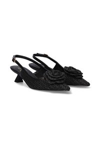 Tacones negros tipo slingback con punta afilada y tela texturizada, que cuentan con un acento floral en la punta y un tacón bajo y cuadrado.