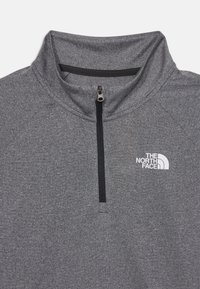 Γκρι μισό-φούτερ με μαύρο φερμουάρ, που διαθέτει λευκό λογότυπο στο αριστερό στήθος. Μαλακό, υφασμάτινο ύφασμα με ραμμένα μανίκια.