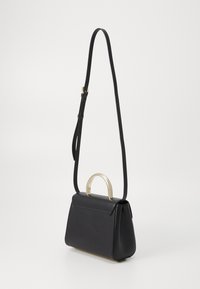 Borsa a mano in pelle nera con una forma strutturata, dotata di un manico superiore in tonalità oro e di una lunga tracolla regolabile. Tessuto liscio, design minimale.