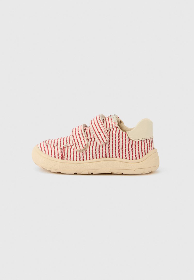 Baskets rayées rouge et blanc avec des sangles en Velcro, un talon couleur crème et une semelle en caoutchouc texturée beige.
