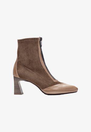 Stivale alla caviglia in suede marrone con punta affusolata, dettagli in pelle e tacco a blocco texture. Presenta una zip laterale e un design a pannelli a contrasto.