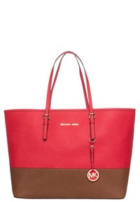 Červená syntetická taška přes rameno s dvěma uchy, hnědým dnem, zlatým logem a přívěskem. Má hladkou texturu a minimalistický design.