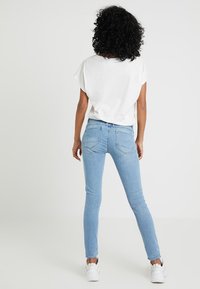 Smala jeans i ljusblå denim med medelhög midja, två bakfickor och smal passform. Matchas med en vit, lös t-shirt.