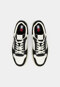 Paire de baskets Tommy Jeans noir et blanc avec lacets, vue de dessus sur un fond clair uni.