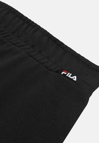 Zwarte elastische tailleband van kleding met een klein Fila-logolabeltje dat dicht bij de naad is genaaid.