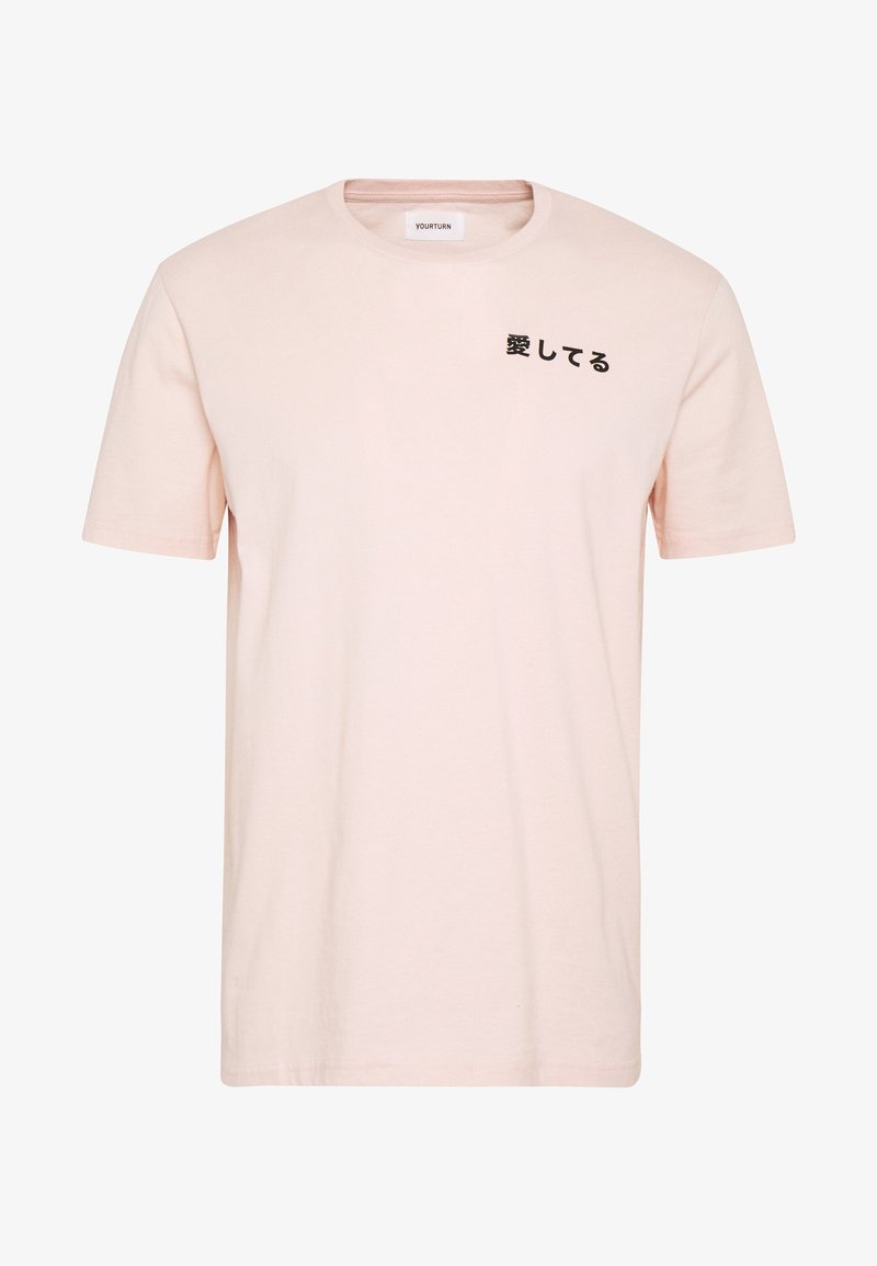 Hellrosa Baumwoll-T-Shirt mit kurzen Ärmeln und rundem Halsausschnitt, mit schwarzem japanischem Text auf der Vorderseite bedruckt.