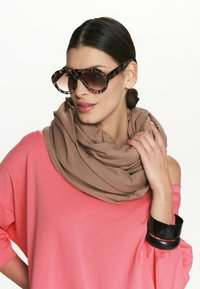 Przesadne okulary przeciwsłoneczne w panterkę, brązowy swobodny szalik i koralowy luźny top z czarnymi bransoletkami.