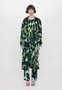 Long, multicolored coat featuring a green, blue, and black abstract pattern, with a belted waist, paired with matching pants.