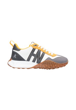 Zapatillas blancas, grises y amarillas con logo negro, cordones blancos y suela marrón texturizada diseñadas para uso al aire libre o casual.