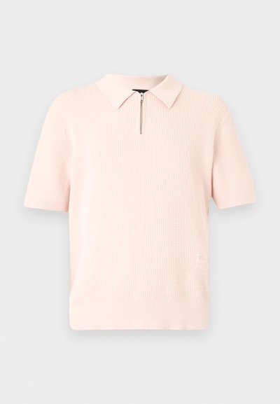 Φωτεινό ροζ πλεκτό πόλο με κοντά μανίκια, υφή, γιακά και κοντό ασημένιο φερμουάρ στη λαιμόκοψη.