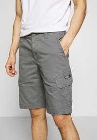 Harmaat puuvillaiset cargo-shortsit, joissa sivutaskut, eteen kiinnitettävä nappikiinnitys ja näkyvät ompelusaumat kestävyyttä varten.