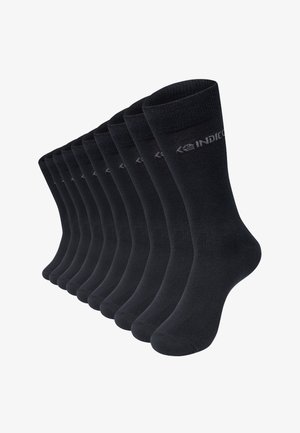 Dix paires de chaussettes noires montantes avec un logo discret près de la tige supérieure, disposées en éventail.