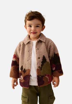 Løs, beige shearling jakke med farverige bjergmønstre, knaplukning og spidse krave. Matcher med en hvid skjorte og olivengrønne cargo bukser.