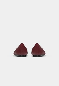 Sapatilhas de couro borgonha com um design de bico apontado, apresentando uma textura suave e um salto baixo preto. Adequadas para uso casual e formal.