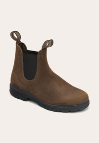 Botín Chelsea de cuero marrón con paneles laterales elásticos, puntera redondeada y tiradores. Cuenta con una suela de goma para tracción y durabilidad.