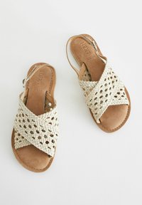 Geflochtene sandfarbene Ledersandalen mit Kreuzriemen und einem Rückenslingback-Design, ausgestattet mit einer glatten Fußbett und einer flexiblen Sohle.
