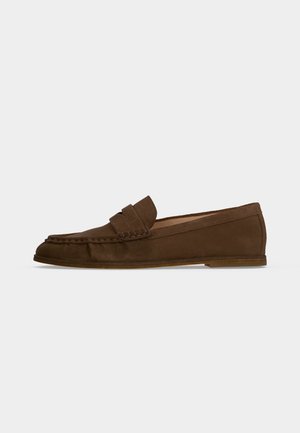 Hnedý semišový penny loafer s prešitým špicom moc toe a plochou podrážkou na čistom bielom pozadí.