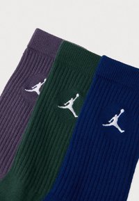 Tri ribane čarape do kubota u ljubičastoj, zelenoj i plavoj boji, svaka sa bijelim Jumpman logom našivenim blizu manžeta.