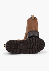 Botine din suede maro, cu talpă din cauciuc, model texturat pe talpă și cu o bandă de prindere. Prezintă cusături și un toc contrastant.