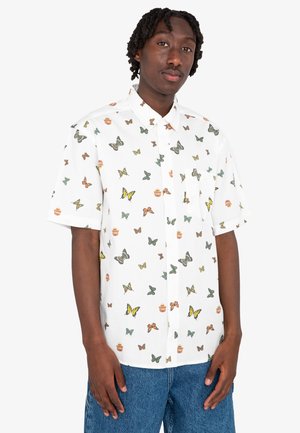 Camisa blanca de manga corta con botones que presenta un patrón de mariposas y tarros en varios colores. La tela es ligera y tiene una textura suave.