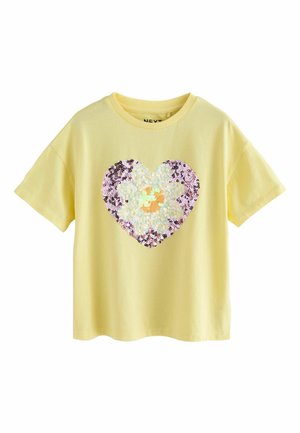 T-shirt jaune à manches courtes avec un motif de cœur en sequins orné d'une grande marguerite au centre.
