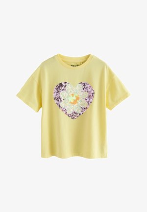 Kollane lühikeste varrukatega t-särk, millel on litritega südamekujuline muster, keskel suur karikakra.