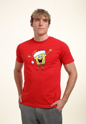 Rød bomulds t-shirt med en tegneseriefigur i en nissehue, med korte ærmer og rund hals. Designet er centralt placeret og farverigt.