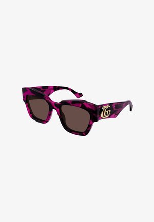 Lunettes de soleil œil de chat à motif écaille de tortue violet et noir, verres foncés et logo double G en or sur la branche.