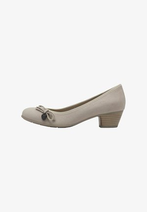 Beige Wildleder-Pumps mit einem runden Zehenbereich, dekorativem Schleifen vorne und einem kleinen Herzanhänger. Rilliertes Holzabsatzdetail.