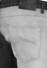 Los jeans de mezclilla gris cuentan con un solo bolsillo trasero con costuras visibles y una etiqueta de cuero attachada a la cinturilla.