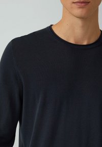 Marineblauwe lange mouwen gebreide top met ronde hals, met een gladde textuur en subtiele stikdetails bij de schouders.