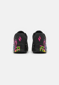 Schwarze Sneaker mit strukturiertem Rückteil, das ein buntes grafisches Design in Rosa, Grün, Gelb und blauen Akzenten an der Ferse aufweist.