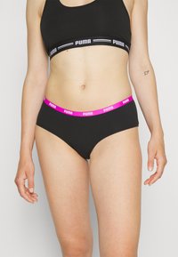 Crni bikini s ružičastim elastičnim pojasom na kojem se nalazi "PUMA" logo. Mekana tkanina s glatkom teksturom i klasičnim krojem gaćica.