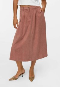 Jupe midi plissée en tissu rose doux ; dotée d'une taille, de deux poches latérales et d'une coupe décontractée. Assortie à des chaussures à bout pointu en imprimé serpent.