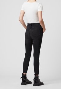 Svarta, högmidjade skinny jeans med en mjuk denimtextur. Innehåller två bakfickor och en tight passform, kombinerat med svarta kängor.