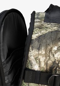 Batoh v kamuflážovom vzore s textúrovaným povrchom, polstrovaným vnútrom, čiernymi akcentmi a nastaviteľným popruhom. S prednou časťou na zips pre ľahký prístup.