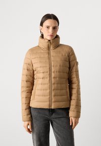 Lysbrun pufferjakke med høj krave, vandret stitching og lynlåslukning foran. Har sidelommer og en tætsiddende design.