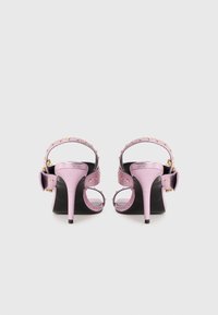 Purple metallic high-heeled sandals with an open back, embellished straps, and gold studs, featuring a bow accent on the heel.