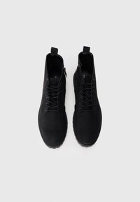 Μαύρες σουέτ μπότες ankle με δέσιμο και φερμουάρ, στρογγυλή μύτη, επενδεδυμένο πέλμα και υβριδιωτό καουτσούκ σόλα. Μινιμαλιστικός σχεδιασμός.