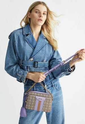 Sac à motifs marron avec des accents lavande et une bandoulière chaînée, associé à une veste en denim bleue et un jean taille haute.