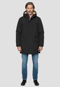 Parka noire isolante avec capuche et doublure en polaire, dotée d'une fermeture éclair frontale, de deux grandes poches poitrine et de poches latérales à boutons.