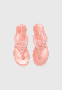 Rosa transparenta flip-flops med ett tångdesign, utrustade med en cirkulär logotypdetalj och en blank yta. Slät textur hela vägen igenom.