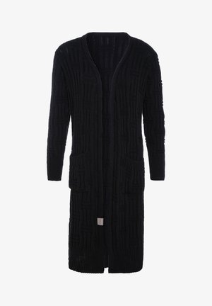 Lange zwarte gebreide cardigan met een textuur van geometrische patronen, open voorkant, twee voorzakken en lange mouwen.